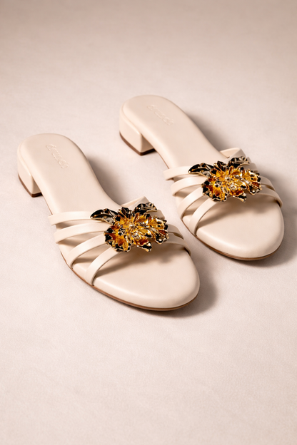 Everglow Flat Sandals in Off White – Detail View of Gold Floral Buckle Embellishment | Drunch